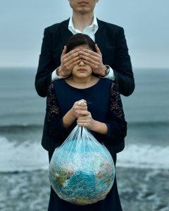 Fille tenant un globe enveloppé de plastique, représentant le changement climatique et la négligence environnementale