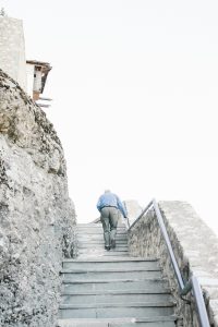 Un homme en chemise bleue monte des escaliers en pierre en plein air entouré de rochers.