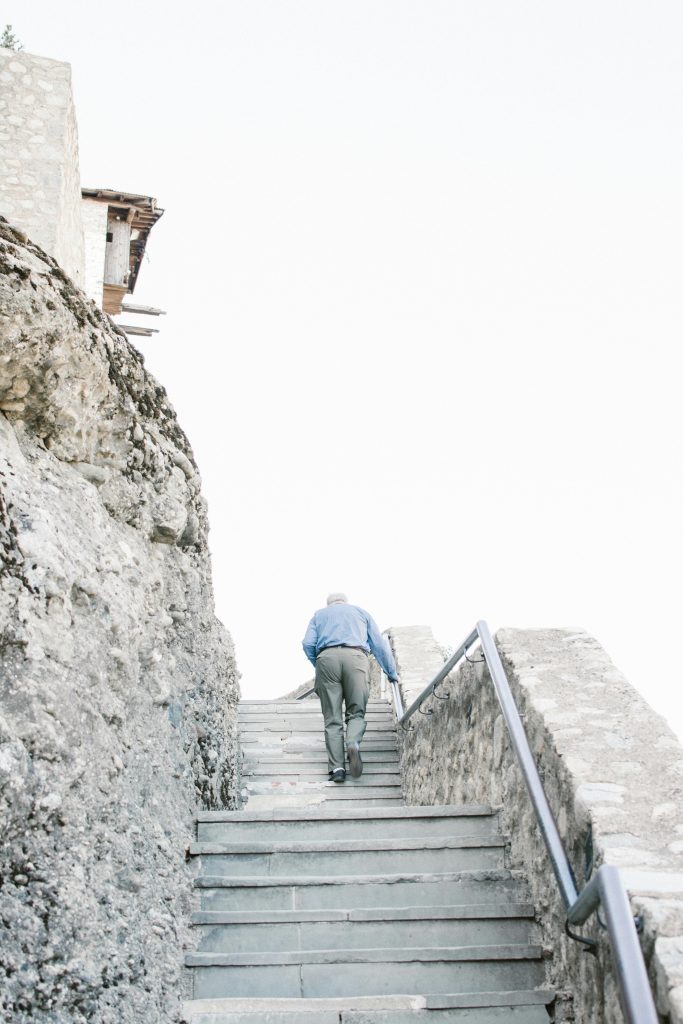 Un homme en chemise bleue monte des escaliers en pierre en plein air entouré de rochers.