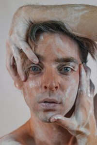 Close-up artistique d'un portrait avec de la poudre blanche mettant en valeur des traits expressifs.