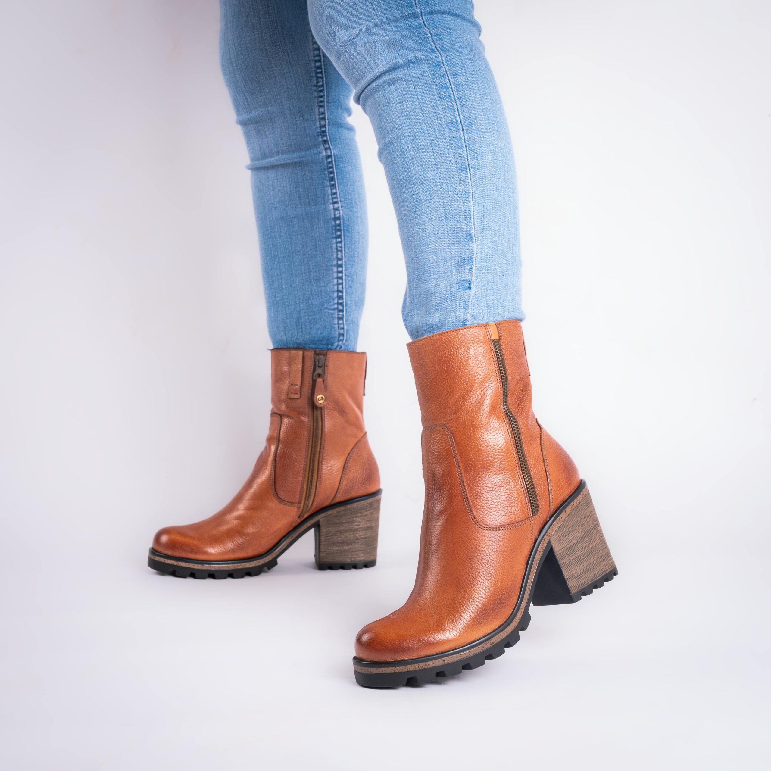 Elegantes bottines en cuir marron associées à un jean décontracté sur fond blanc.