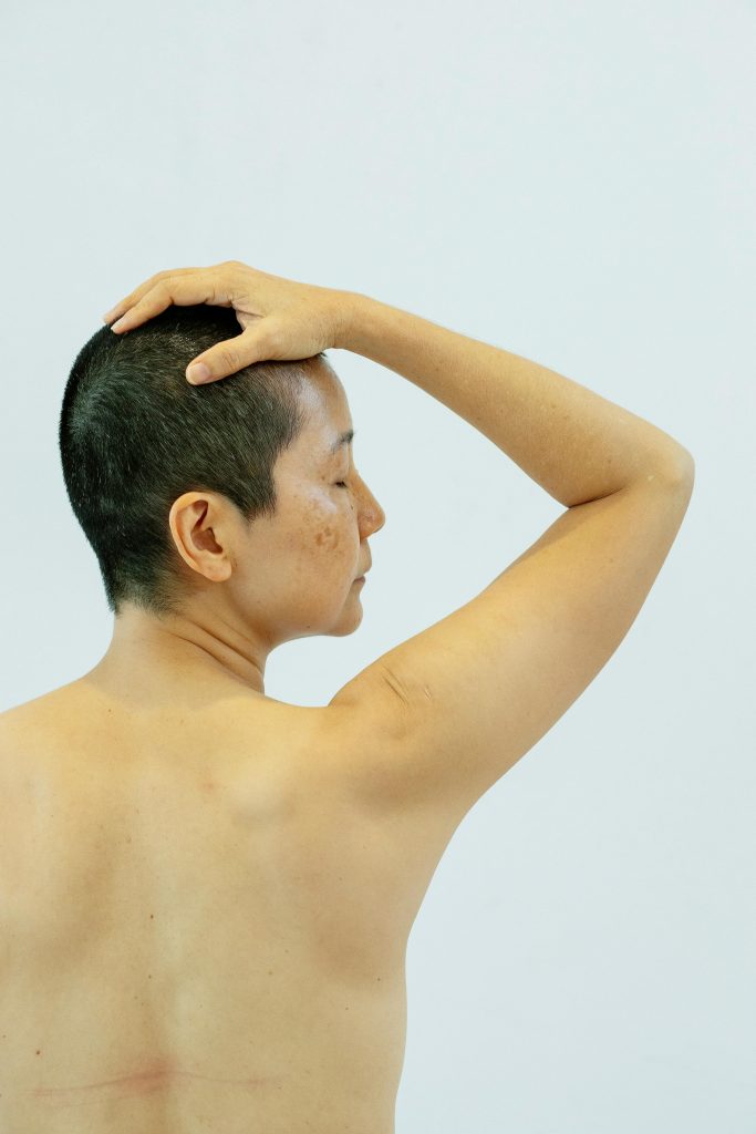 Dos d'une femme ethnique torse nu les yeux fermés sur fond blanc de studio