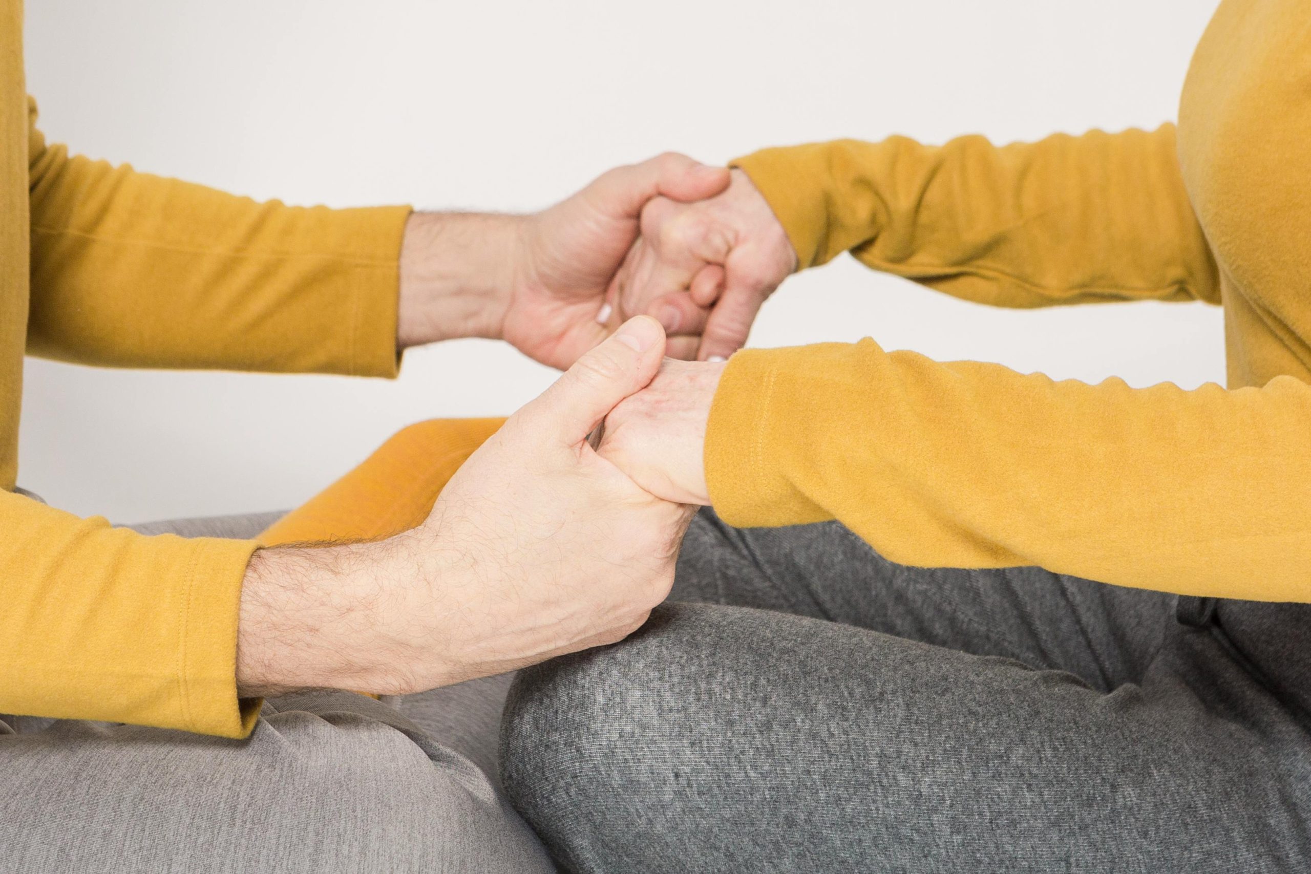 A gros plan de deux adultes se tenant la main dans un geste de soutien et d'amour.