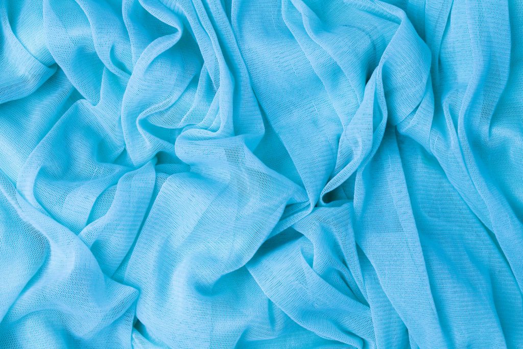 Détail d'un tissu bleu texturé avec des plis complexes, parfait pour des fonds textiles.