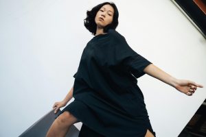 Artistique portrait d'une femme asiatique posant de manière dramatique dans une robe noire sur un fond blanc
