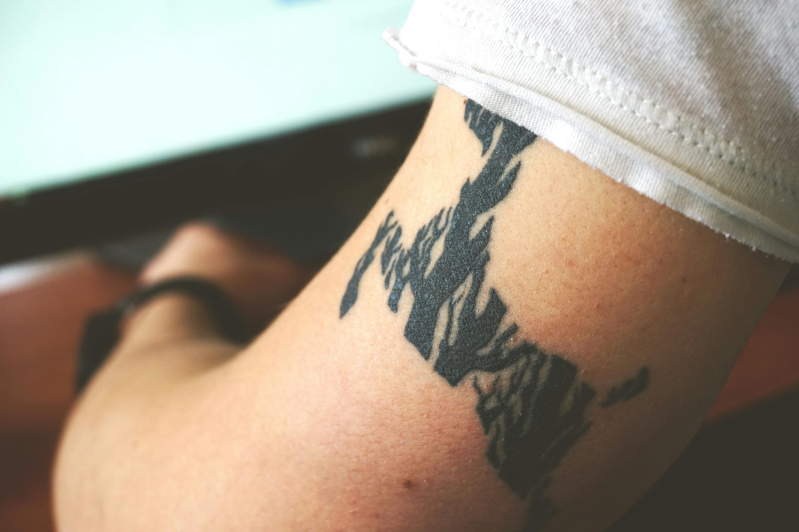 Détail en gros plan d'un tatouage abstrait noir sur le bras d'une personne, mettant en valeur une œuvre corporelle personnelle.