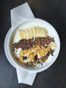 Delicious granola yogurt bowl garni de tranches de banane et de copeaux de chocolat.