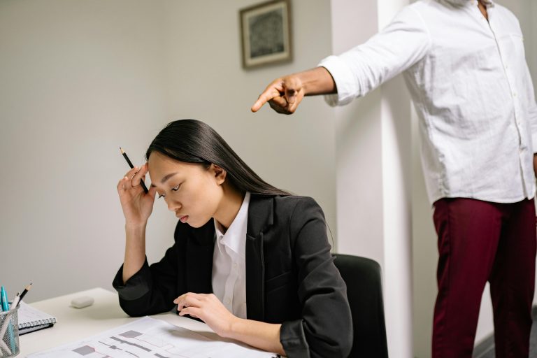 An office scenario depicting a young woman experiencing bullying from a coworker. Un scénario de bureau montrant une jeune femme victime de harcèlement de la part d'un collègue.