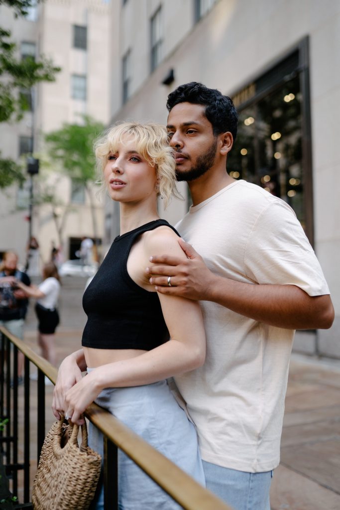 A couple embraces warmly in a bustling city street, showcasing love and togetherness. Un couple s'embrasse chaleureusement dans une rue animée de la ville, montrant l'amour et la communion.