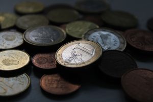A close-up shot of Euro coins in various denominations scattered on a dark surface. Un gros plan de pièces en euros de diverses dénominations éparpillées sur une surface sombre.