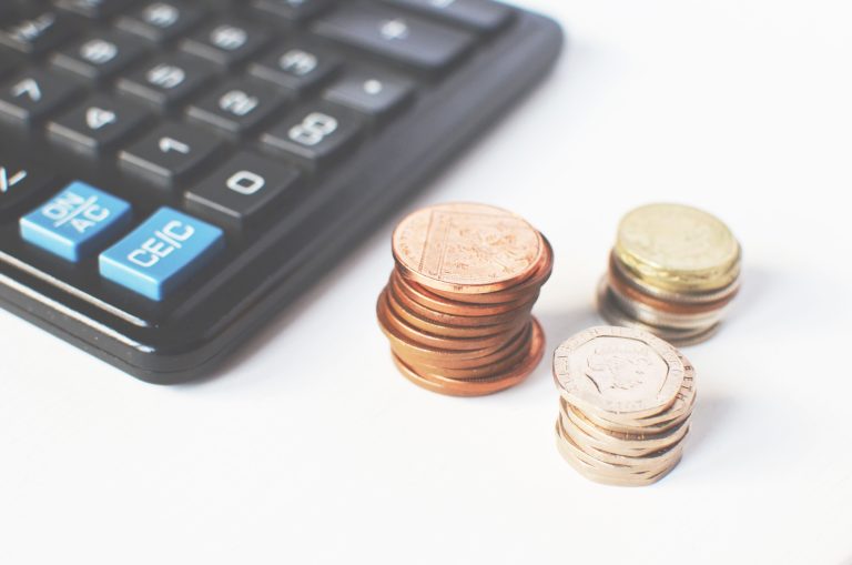 Close-up of stacked coins and a calculator symbolizing financial strategy and budgeting. Gros plan sur des pièces empilées et une calculatrice symbolisant la stratégie financière et la budgétisation.