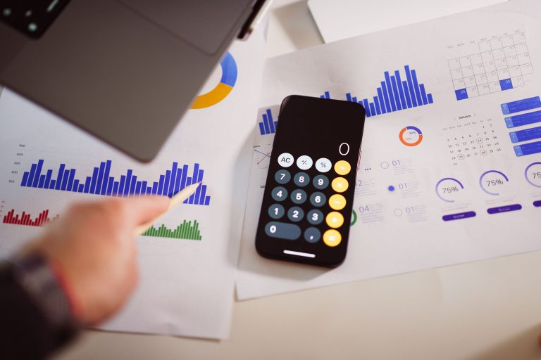 Business analytics setup with calculator, graphs, and laptop, showcasing financial insights. Configuration d'analyse commerciale avec calculatrice, graphiques et ordinateur portable, mettant en évidence les informations financières.